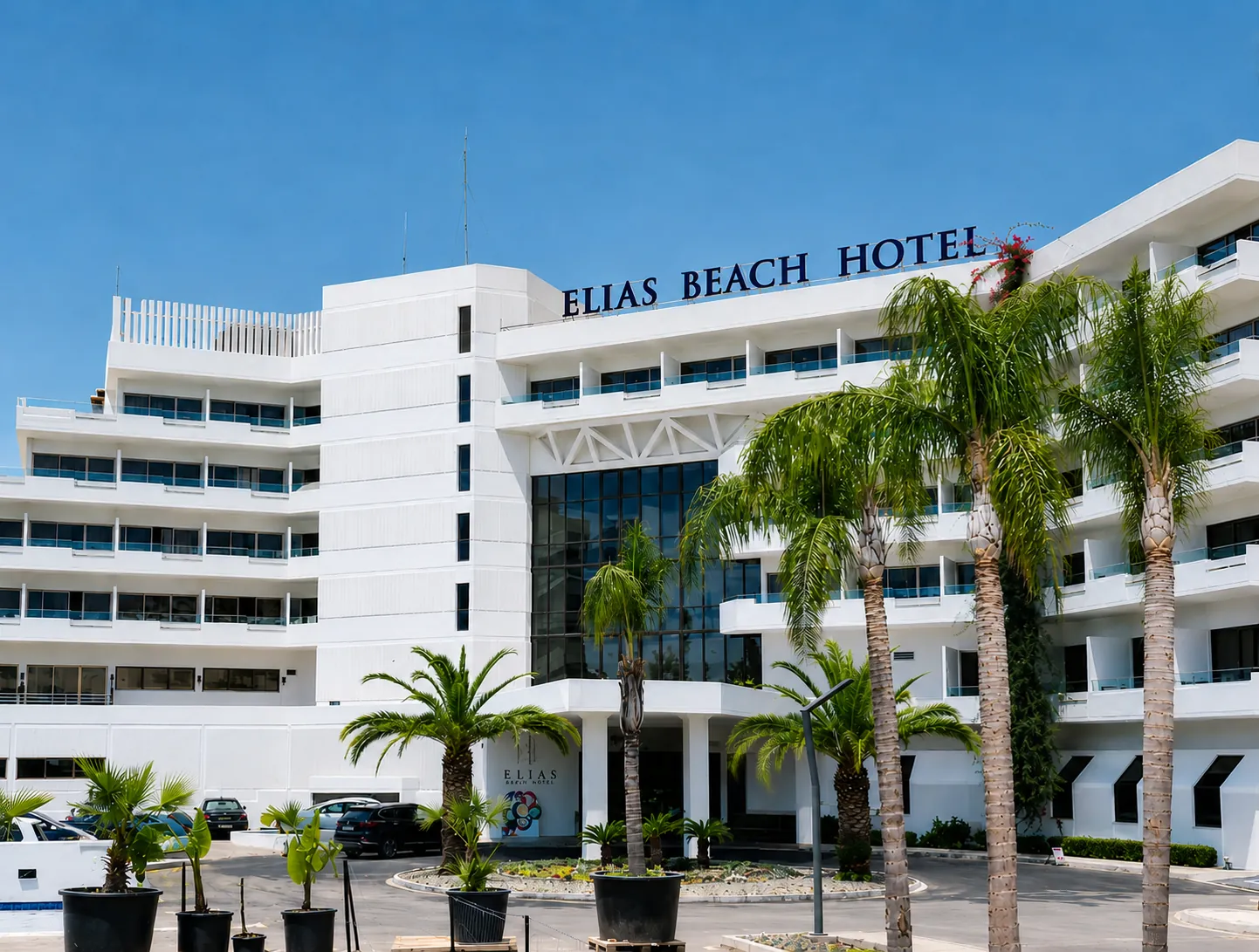 Elias Beach Hotel entrance with palm trees and the hotel sign on the facade